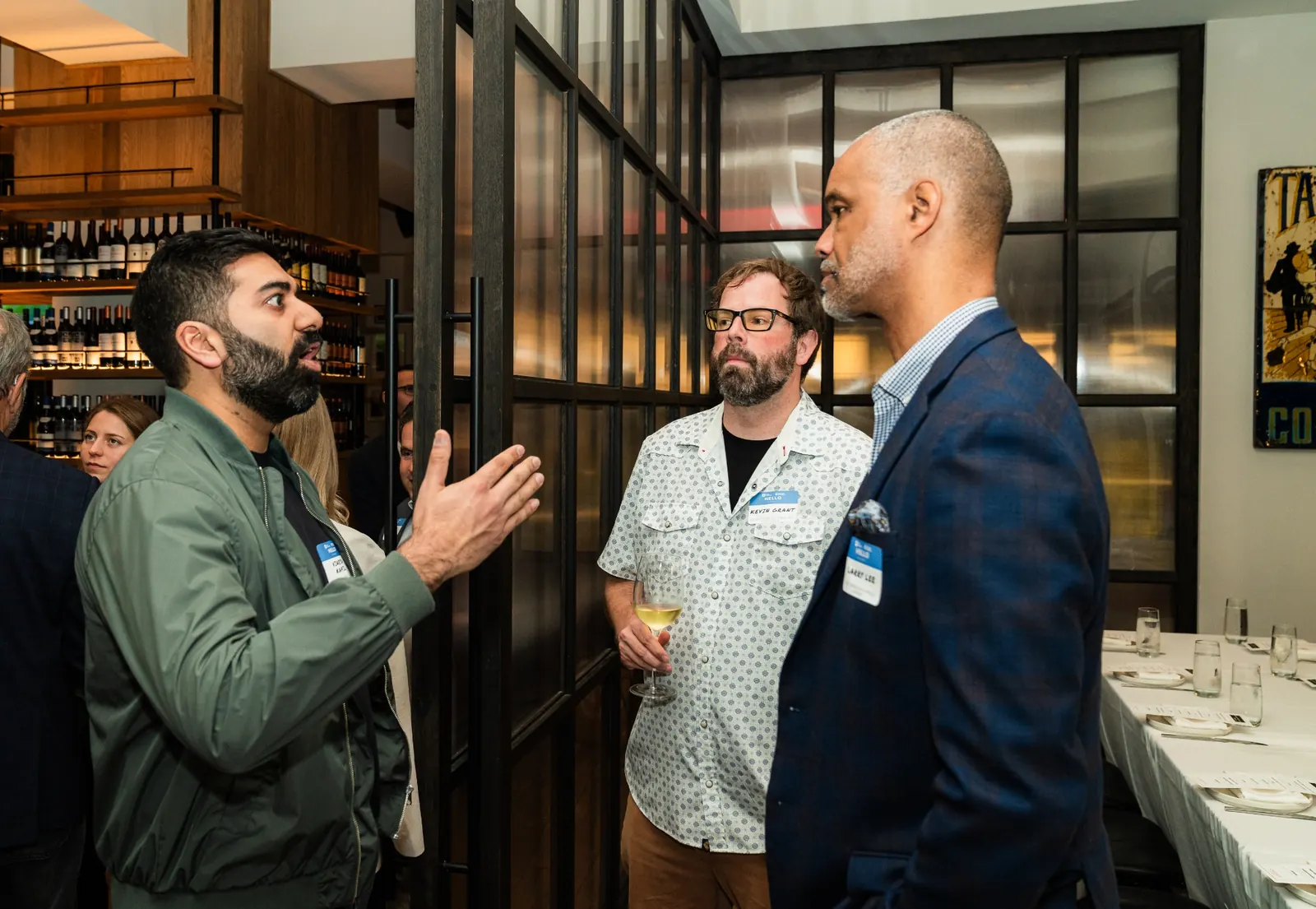Three attendees deep in discussion at the bar
